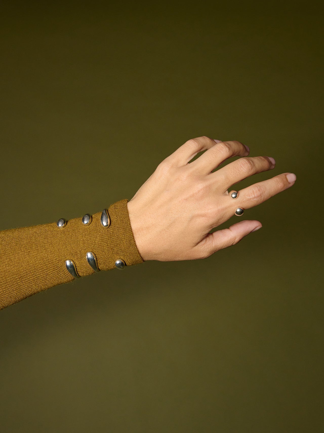 Sterling Silver Torque Ring pictured on models pointer finger. The Torque Cuff is pictured stacked on models wrist. 