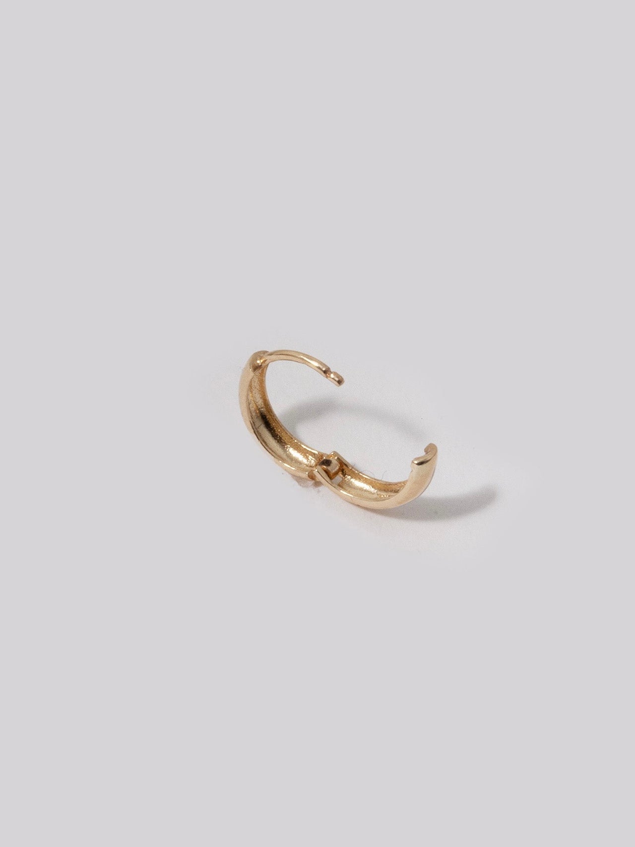 14kt Yellow Gold Anelli Huggies shot on light grey background.