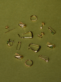 14kt Yellow Gold Mini Diamond Tsavorite Safety Pin included in multi-product flat lay. Green background. 