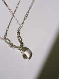 Sterling Silver Stone Teardrop Necklace pictured on light grey background in the sun. 