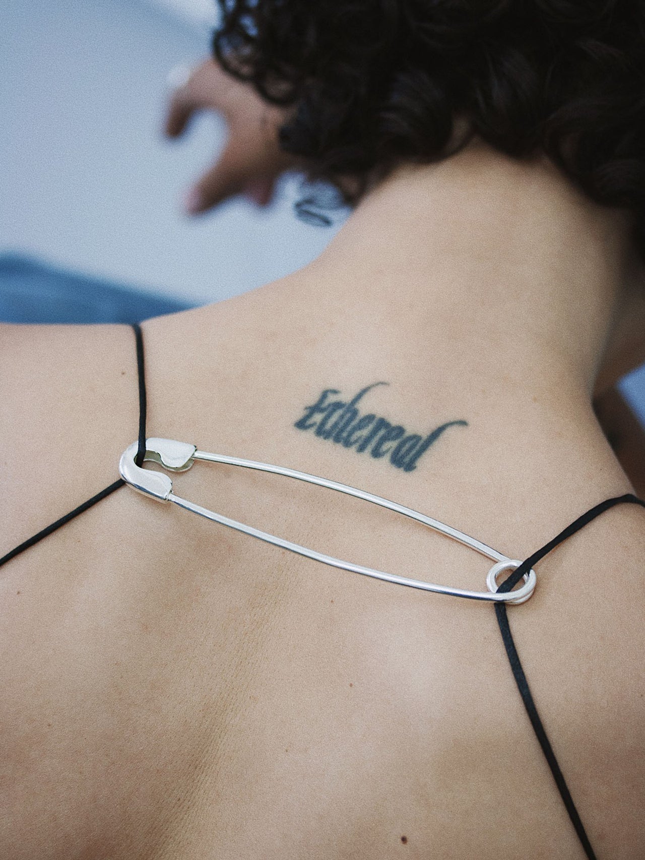 Jumbo Safety Pin pictured on models back, holding straps together. 