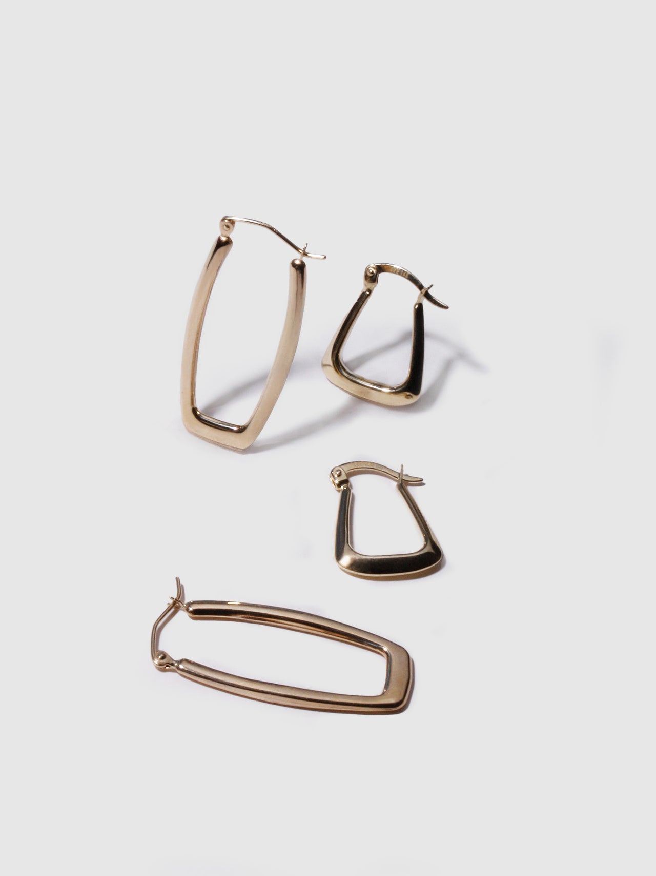 Flat lay of 14kt Yellow Gold Hoops Trifecta Hoops and Squoval Hoops.