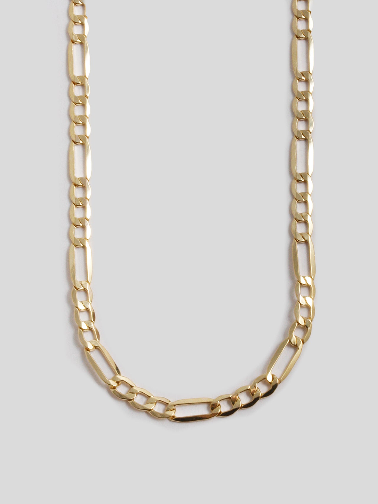 Close up of 14Kt Yellow Gold XL Hollow Figaro Chain on light grey background.