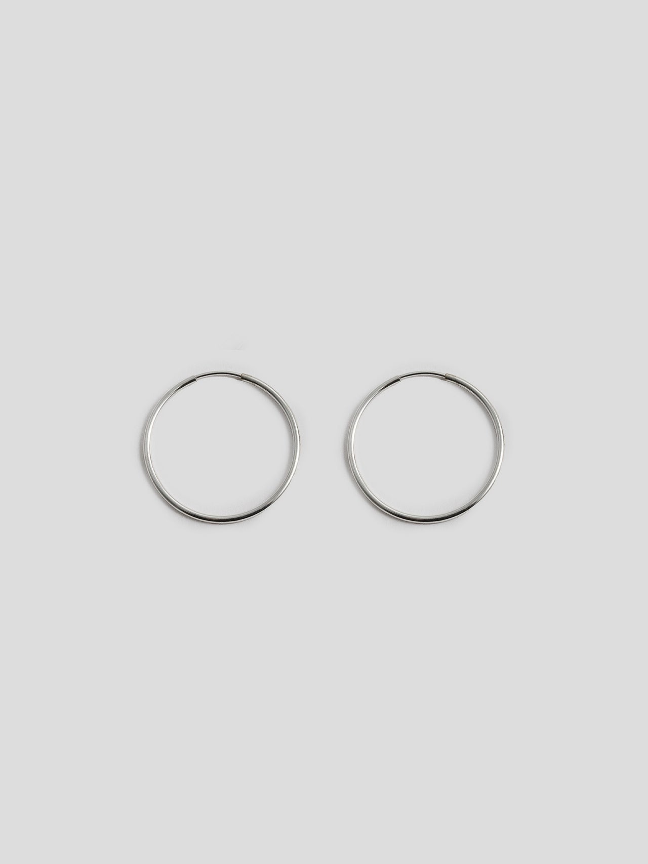 Sterling Silver Infinity Hoops shot on light grey background.