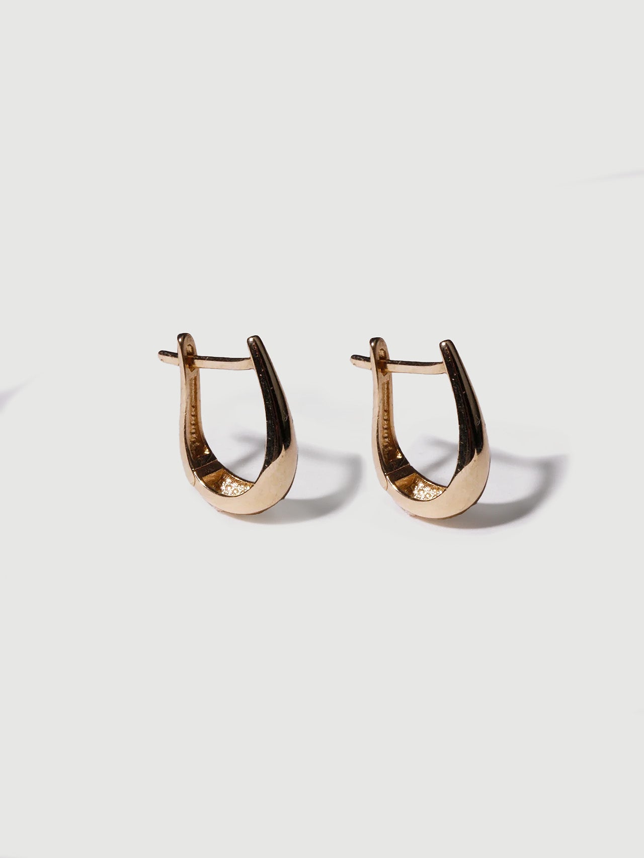 14kt Yellow Gold Cleopatra Huggies pictured standing up right on light grey background. 