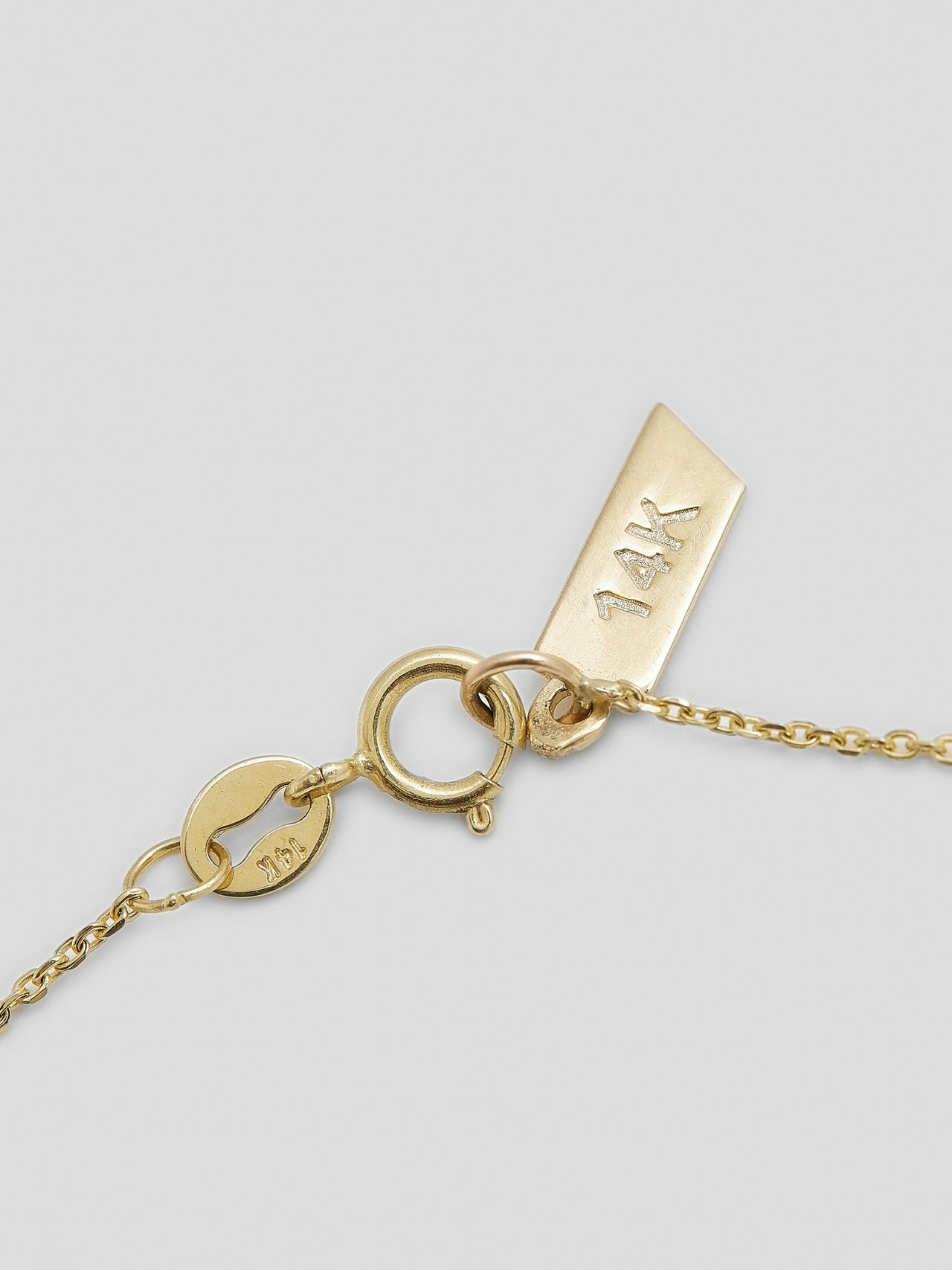 Close up of clasp on thin yellow gold chain necklace. 